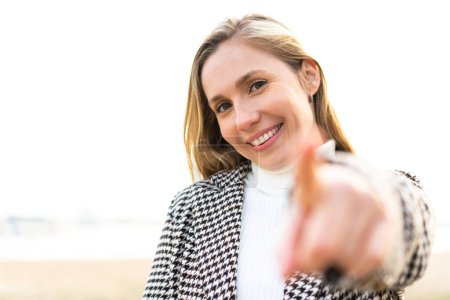 Téléchargez les photos : Jeune femme blonde à l'extérieur pointe du doigt vers vous avec une expression confiante - en image libre de droit