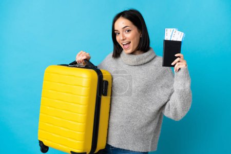 Photo for Young caucasian woman isolated on blue background in vacation with suitcase and passport - Royalty Free Image