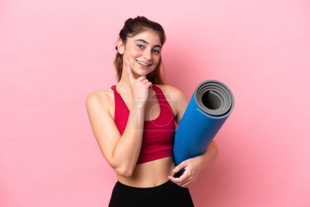 Téléchargez les photos : Young sport woman going to yoga classes while holding a mat thinking an idea while looking up - en image libre de droit