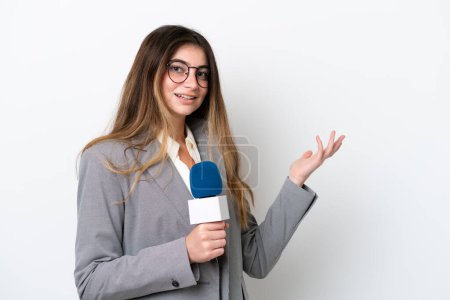 Téléchargez les photos : Jeune présentateur de télévision caucasienne femme isolée sur fond blanc étendant les mains sur le côté pour inviter à venir - en image libre de droit
