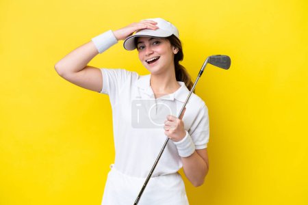 Téléchargez les photos : Jeune femme caucasienne jouer au golf isolé sur fond jaune souriant beaucoup - en image libre de droit