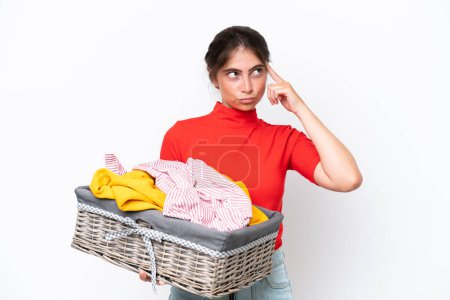 Photo for Young caucasian woman holding a clothes basket isolated on white background having doubts and thinking - Royalty Free Image