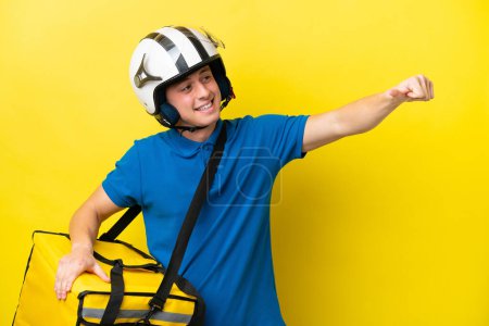 Foto de Young Brazilian man with thermal backpack isolated on yellow background giving a thumbs up gesture - Imagen libre de derechos