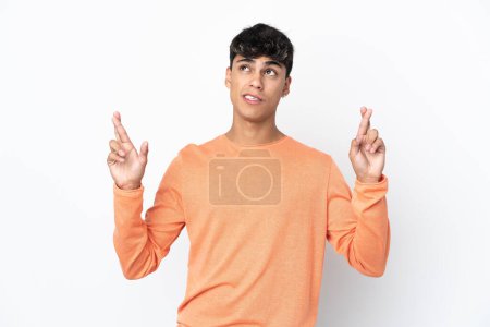 Photo for Young man over isolated white background with fingers crossing and wishing the best - Royalty Free Image