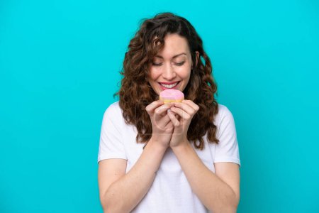 Photo for Young caucasian woman isolated on blue background holding a donut - Royalty Free Image