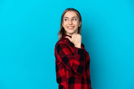 Téléchargez les photos : Jeune femme caucasienne isolée sur fond bleu pointant vers le côté pour présenter un produit - en image libre de droit