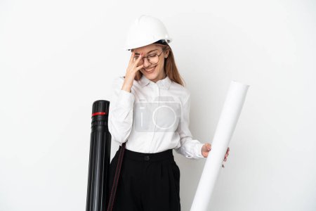 Foto de Young architect woman with helmet and holding blueprints isolated on white background laughing - Imagen libre de derechos