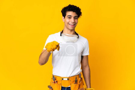 Photo for Venezuelan electrician man isolated on yellow background surprised and pointing front - Royalty Free Image
