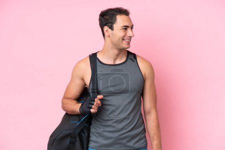 Photo for Young sport caucasian man with sport bag isolated on pink background looking side - Royalty Free Image