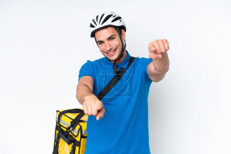 Téléchargez les photos : Young caucasian man with thermal backpack isolated on white background points finger at you while smiling - en image libre de droit