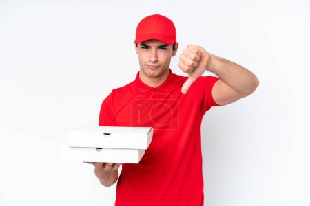 Foto de Entrega de pizza hombre caucásico con uniforme de trabajo recogiendo cajas de pizza aisladas sobre fondo blanco mostrando el pulgar hacia abajo con expresión negativa - Imagen libre de derechos