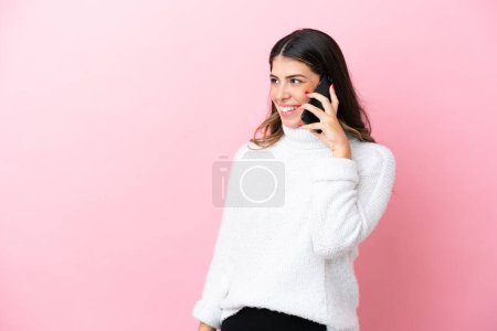 Photo for Young Italian woman isolated on pink background keeping a conversation with the mobile phone with someone - Royalty Free Image