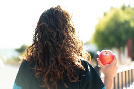 Téléchargez les photos : Jeune femme sportive avec une pomme à l'extérieur en position arrière - en image libre de droit