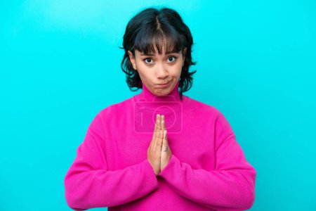 Photo for Young Argentinian woman isolated on blue background keeps palm together. Person asks for something - Royalty Free Image