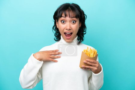 Photo for Young Argentinian woman holding fried chips isolated on blue background surprised and shocked while looking right - Royalty Free Image