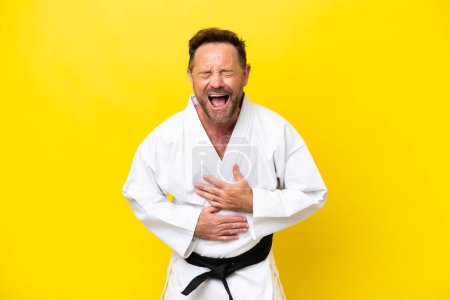 Foto de Hombre caucásico de mediana edad haciendo karate aislado sobre fondo amarillo sonriendo mucho - Imagen libre de derechos