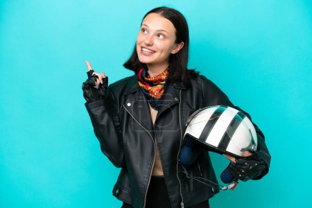 Téléchargez les photos : Jeune femme caucasienne avec un casque de moto isolé sur fond bleu pointant vers le haut d'une excellente idée - en image libre de droit