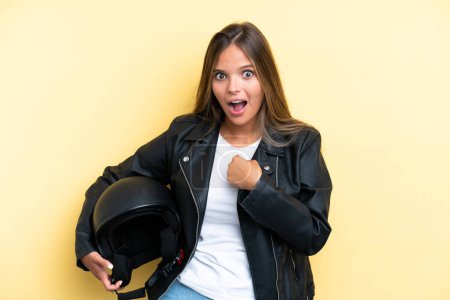 Foto de Mujer joven caucásica con casco de moto aislado sobre fondo amarillo con expresión facial sorpresa - Imagen libre de derechos