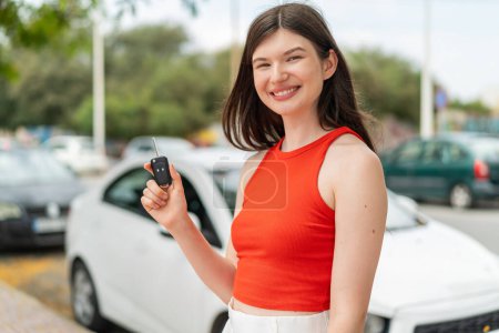 Photo for Young pretty Ukrainian woman holding car keys at outdoors smiling a lot - Royalty Free Image
