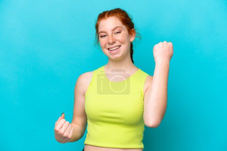 Photo for Young reddish woman isolated on blue background celebrating a victory - Royalty Free Image