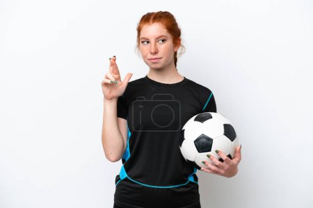 Téléchargez les photos : Jeune joueur de football caucasien rougeâtre femme isolée sur fond blanc avec les doigts croisés et souhaitant le meilleur - en image libre de droit