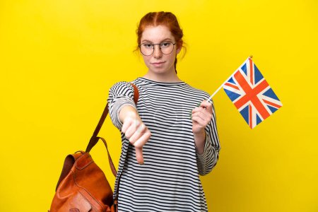 Téléchargez les photos : Jeune femme hispanique tenant un drapeau du Royaume-Uni isolé sur fond jaune montrant le pouce baissé avec une expression négative - en image libre de droit