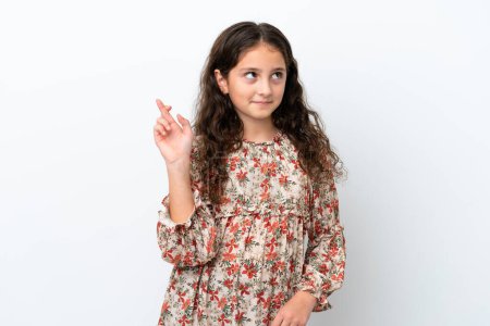 Téléchargez les photos : Petite fille caucasienne isolée sur fond blanc avec les doigts croisés et souhaitant le meilleur - en image libre de droit