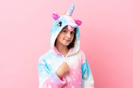 Foto de Pequeña mujer caucásica con un pijama unicornio aislado sobre fondo rosa con expresión facial sorpresa - Imagen libre de derechos