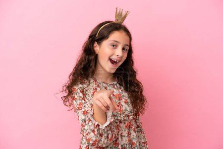Photo for Little caucasian princess with crown isolated on pink background surprised and pointing front - Royalty Free Image