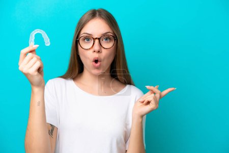 Photo for Young Lithuanian woman holding invisible braces isolated on blue background surprised and pointing side - Royalty Free Image