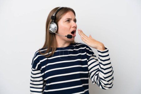 Foto de Telemarketer caucasian woman working with a headset isolated on white background yawning and covering wide open mouth with hand - Imagen libre de derechos