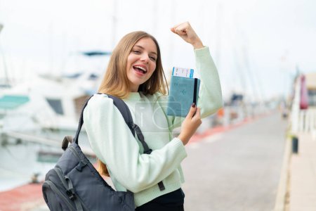 Téléchargez les photos : Jeune jolie femme blonde tenant un passeport et célébrant une victoire - en image libre de droit