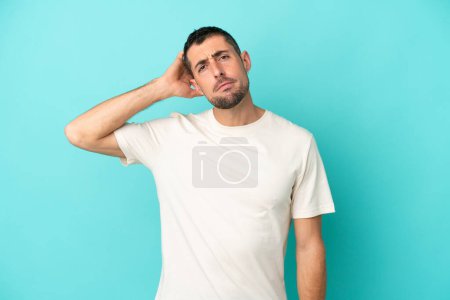 Foto de Joven hombre caucásico guapo aislado sobre fondo azul con una expresión de frustración y falta de comprensión - Imagen libre de derechos