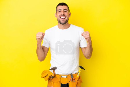 Photo for Young electrician caucasian man isolated on yellow background celebrating a victory in winner position - Royalty Free Image