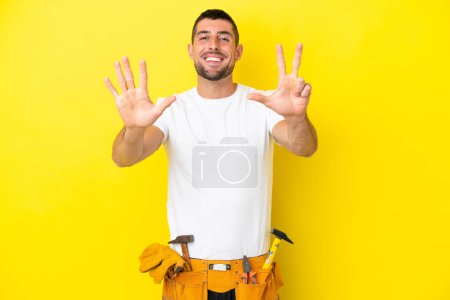 Foto de Joven electricista caucásico aislado sobre fondo amarillo contando ocho con los dedos - Imagen libre de derechos