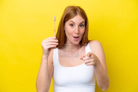 Téléchargez les photos : Jeune rousse femme brossant les dents surpris et pointant devant - en image libre de droit