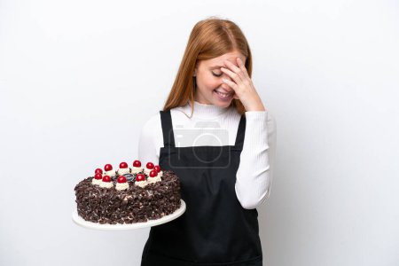 Téléchargez les photos : Jeune rousse femme tenant gâteau d'anniversaire isolé sur fond blanc riant - en image libre de droit