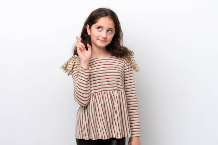 Téléchargez les photos : Petite fille isolée sur fond blanc avec les doigts croisés et souhaitant le meilleur - en image libre de droit