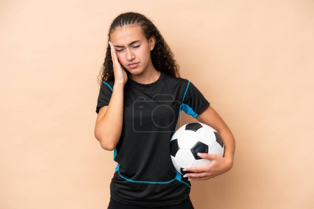 Photo for Young football player woman isolated on beige background with headache - Royalty Free Image