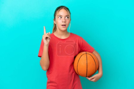 Téléchargez les photos : Petite fille caucasienne jouant au basket isolé sur fond bleu pensant une idée pointant le doigt vers le haut - en image libre de droit