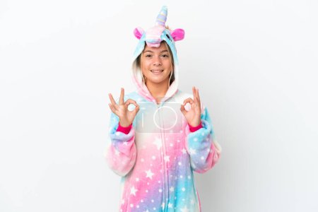 Foto de Niña con pijama de unicornio aislado sobre fondo blanco mostrando un signo aceptable con los dedos - Imagen libre de derechos