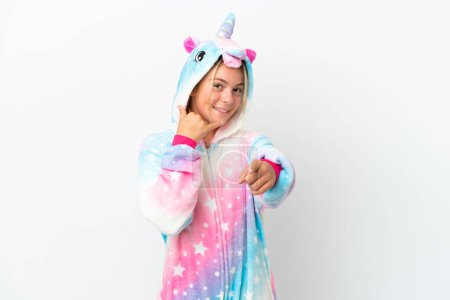 Foto de Niña con pijama de unicornio aislado sobre fondo blanco haciendo gesto telefónico y apuntando hacia delante - Imagen libre de derechos