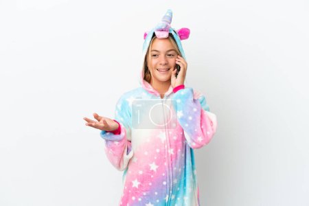 Foto de Niña con pijama de unicornio aislado sobre fondo blanco manteniendo una conversación con el teléfono móvil con alguien - Imagen libre de derechos