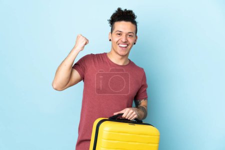 Photo for Caucasian man over isolated blue background in vacation with travel suitcase - Royalty Free Image