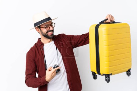 Foto de Hombre viajero con barba sosteniendo una maleta sobre un fondo blanco aislado - Imagen libre de derechos