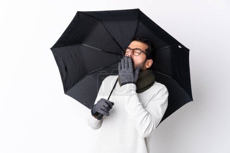 Photo for Caucasian handsome man with beard holding an umbrella over isolated white wall yawning and covering wide open mouth with hand - Royalty Free Image
