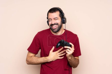 Foto de Hombre jugando con un controlador de videojuegos sobre una pared aislada sonriendo mucho - Imagen libre de derechos
