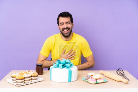 Foto de Hombre en una mesa con un gran pastel sonriendo mucho - Imagen libre de derechos