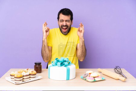 Téléchargez les photos : Homme dans une table avec un gros gâteau avec les doigts croisés - en image libre de droit