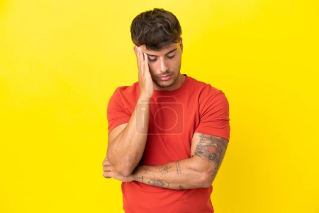 Foto de Joven hombre guapo caucásico aislado sobre fondo amarillo con dolor de cabeza - Imagen libre de derechos